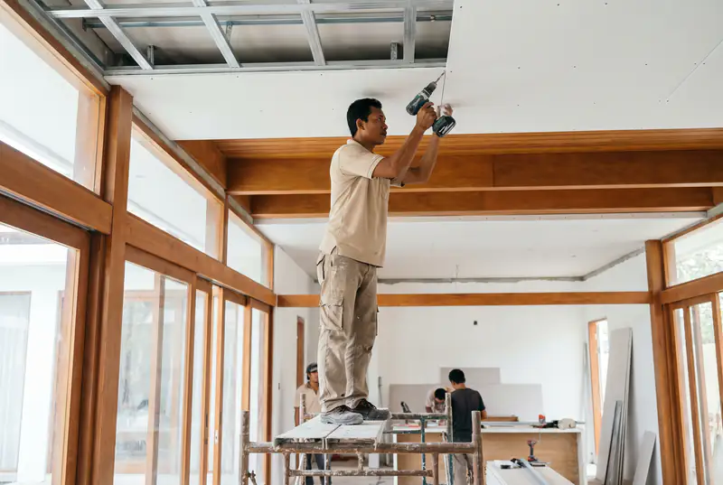 Worker installing a gypsum board ceiling with LED cove detail in a Bali villa