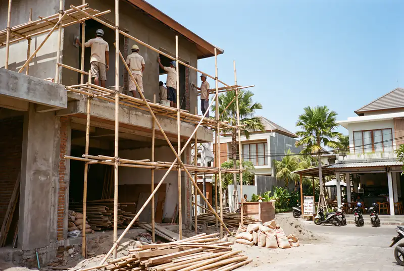 Crew rendering a two-storey villa facade from scaffolding in Berawa Bali