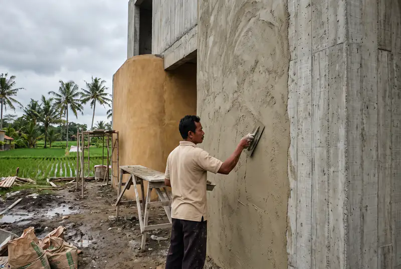 Craftsman applying textured lime plaster to a curved wall in Pererenan Bali