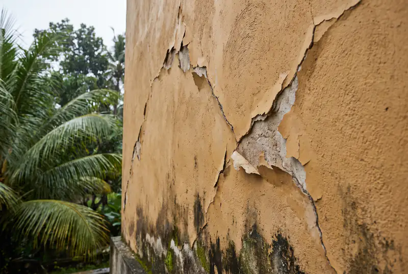 Diagonal shrinkage cracks and moisture damage on a tropical villa wall in Bali